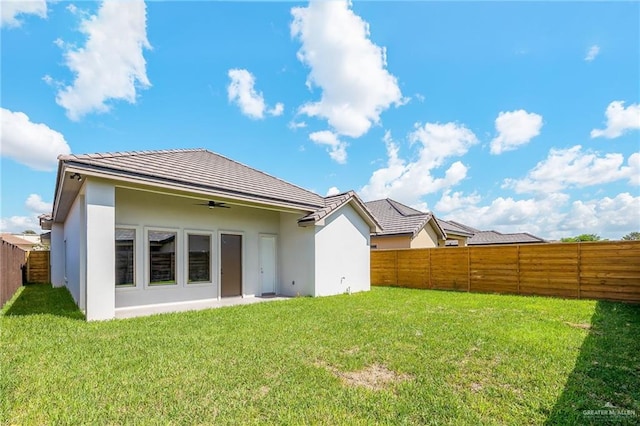 back of property with a fenced backyard, a yard, and stucco siding
