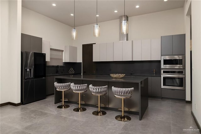 kitchen with stainless steel appliances, dark countertops, modern cabinets, a breakfast bar, and a kitchen island