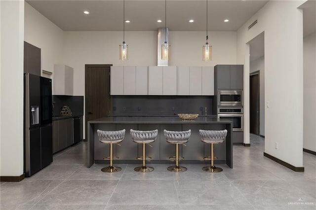 kitchen with hanging light fixtures, a spacious island, modern cabinets, a kitchen bar, and appliances with stainless steel finishes