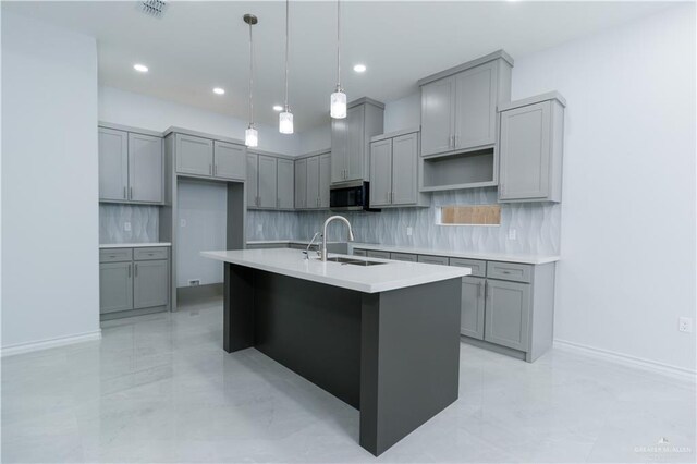 kitchen with sink, decorative backsplash, a kitchen island with sink, and gray cabinets