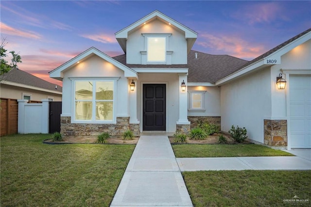 1809 Diplomat Dr, Edinburg, TX 78542 - view of front facade with fence, stone siding, stucco siding, a lawn, and a shingled roof