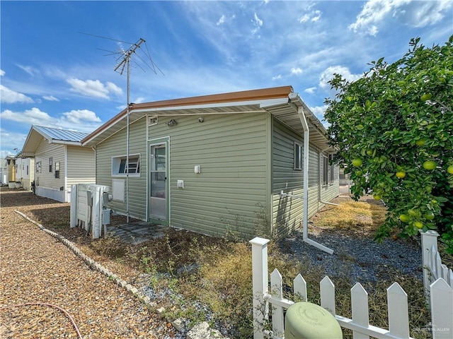 view of side of home featuring metal roof and fence