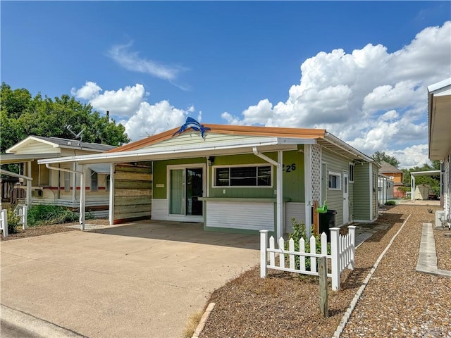 view of front of home with a carport, driveway, and fence