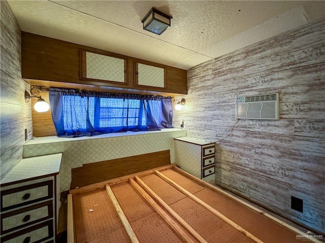 interior space featuring a textured ceiling, wooden walls, and a wall mounted AC