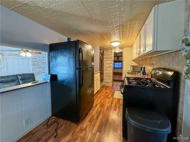 kitchen with range with gas stovetop, freestanding refrigerator, wood finished floors, an ornate ceiling, and a sink