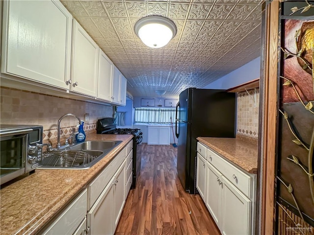 kitchen featuring dark wood-type flooring, black appliances, a sink, an ornate ceiling, and backsplash