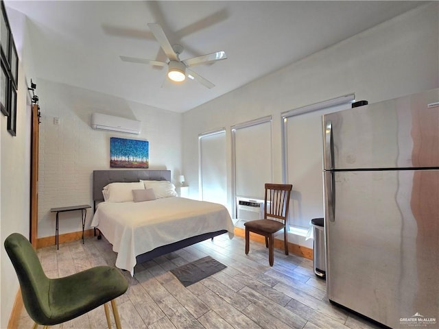 bedroom featuring stainless steel refrigerator, a wall mounted AC, and light wood-type flooring