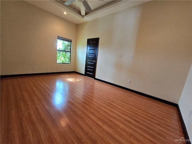 unfurnished room featuring hardwood / wood-style flooring, ceiling fan, and a towering ceiling