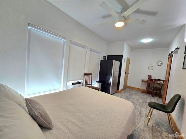 bedroom featuring ceiling fan, a barn door, an AC wall unit, and stainless steel refrigerator