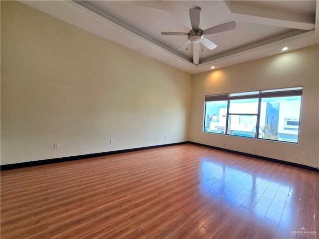 unfurnished room with hardwood / wood-style floors, a tray ceiling, and ceiling fan