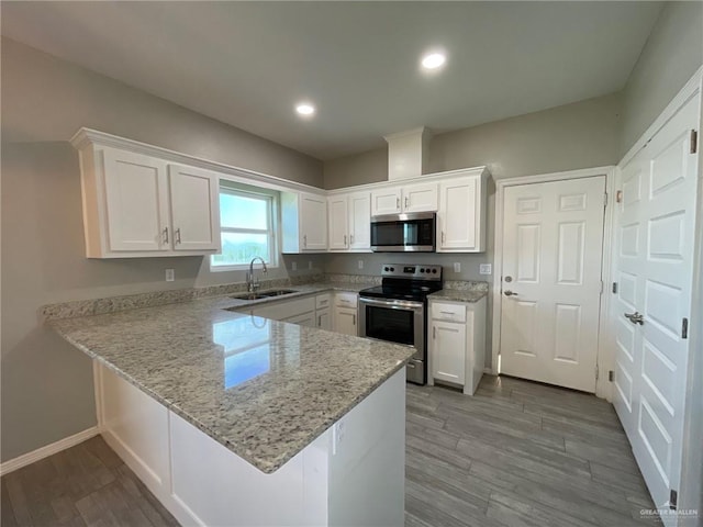 2108 Davenport St, Weslaco, TX 78596 - kitchen with stainless steel appliances, a sink, white cabinets, a peninsula, and wood finished floors