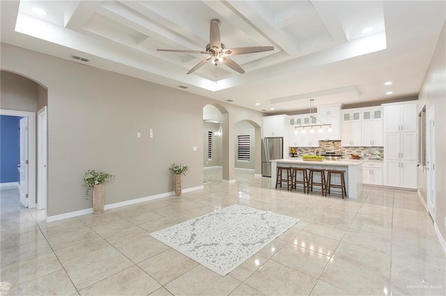 interior space with a breakfast bar, stainless steel refrigerator, hanging light fixtures, white cabinets, and a kitchen island