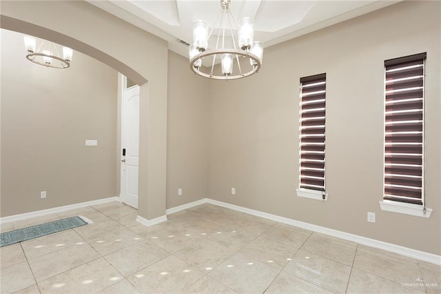 tiled empty room with an inviting chandelier and a raised ceiling