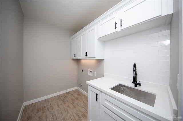 laundry area featuring cabinets, washer hookup, electric dryer hookup, sink, and light hardwood / wood-style flooring