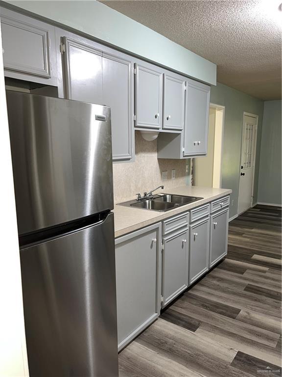 1601 S Oklahoma Ave, Weslaco, TX 78596 - kitchen with freestanding refrigerator, dark wood-style floors, a textured ceiling, light countertops, and gray cabinetry