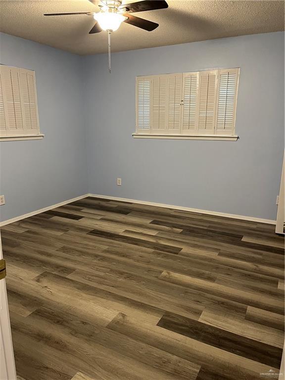 1601 S Oklahoma Ave, Weslaco, TX 78596 - spare room featuring ceiling fan, dark wood-style floors, and a textured ceiling