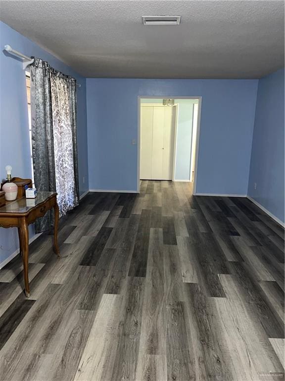 1601 S Oklahoma Ave, Weslaco, TX 78596 - unfurnished room featuring dark wood-style flooring and a textured ceiling