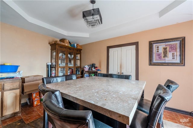 dining room featuring a notable chandelier and a raised ceiling