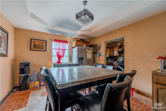 tiled dining room with a raised ceiling