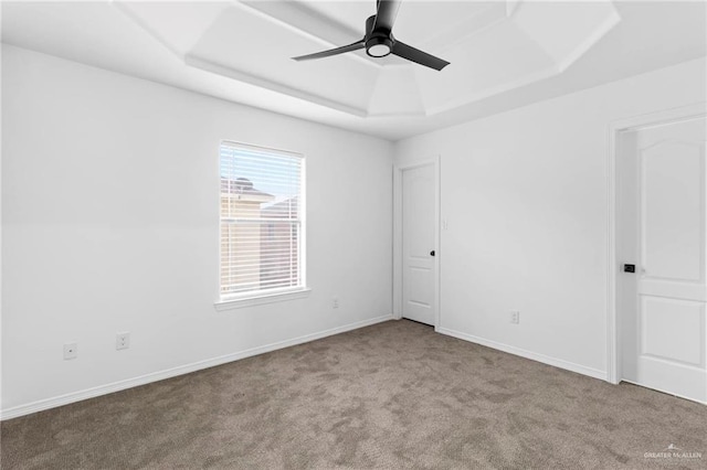 spare room with a raised ceiling, ceiling fan, and light colored carpet