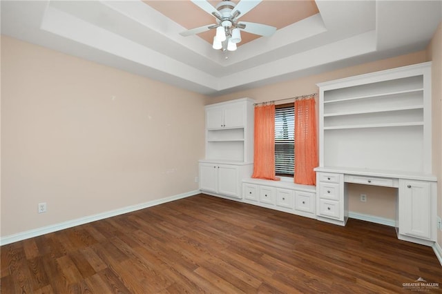 unfurnished bedroom with a raised ceiling, ceiling fan, and dark wood-type flooring