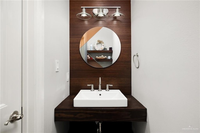 bathroom featuring wooden walls and sink