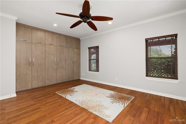 unfurnished bedroom featuring ceiling fan, a closet, ornamental molding, and hardwood / wood-style flooring