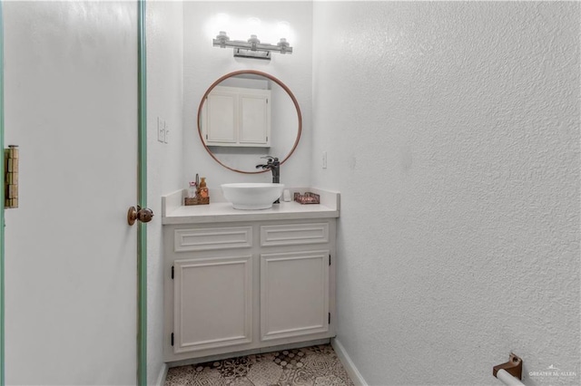 bathroom with vanity, a textured wall, and baseboards