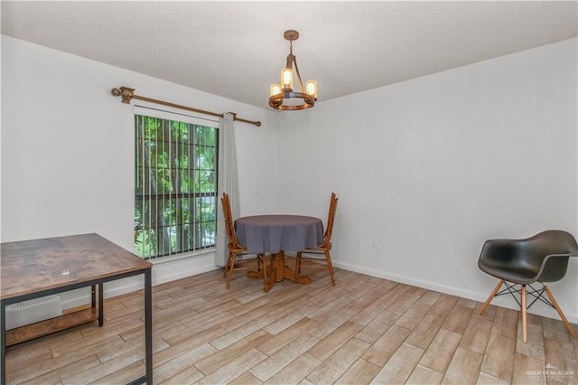 dining space with a notable chandelier, a textured ceiling, baseboards, and wood finished floors