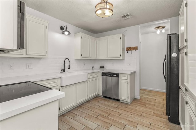 kitchen featuring wood finish floors, visible vents, a sink, stainless steel dishwasher, and freestanding refrigerator