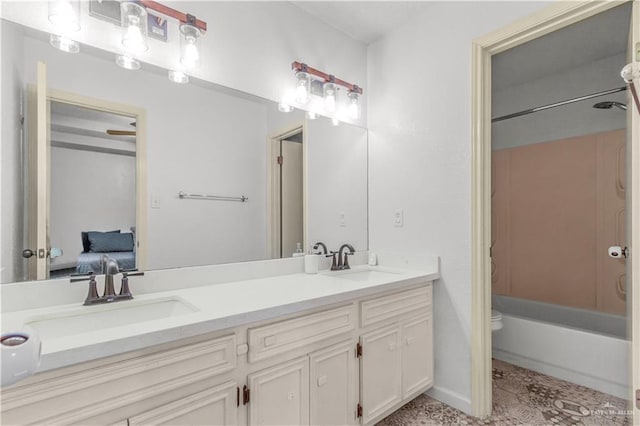 bathroom featuring toilet, double vanity, shower / washtub combination, and a sink