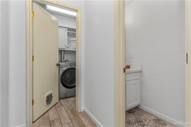 washroom with washer / clothes dryer, cabinet space, baseboards, and wood finish floors