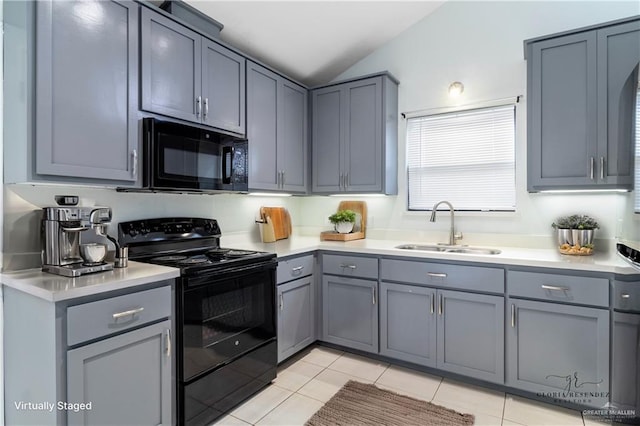 kitchen with vaulted ceiling, sink, black appliances, light tile patterned floors, and gray cabinets