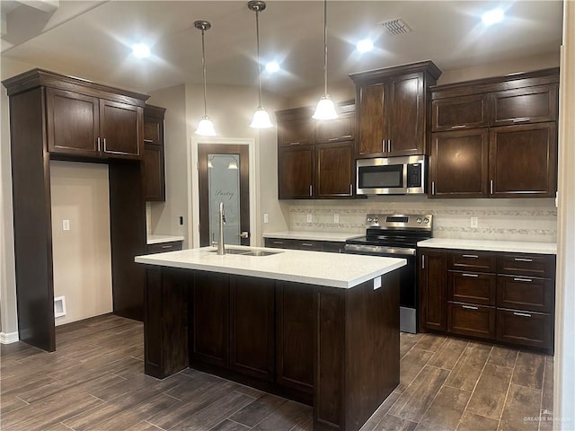 kitchen with stainless steel appliances, dark wood-type flooring, a sink, dark brown cabinets, and light countertops