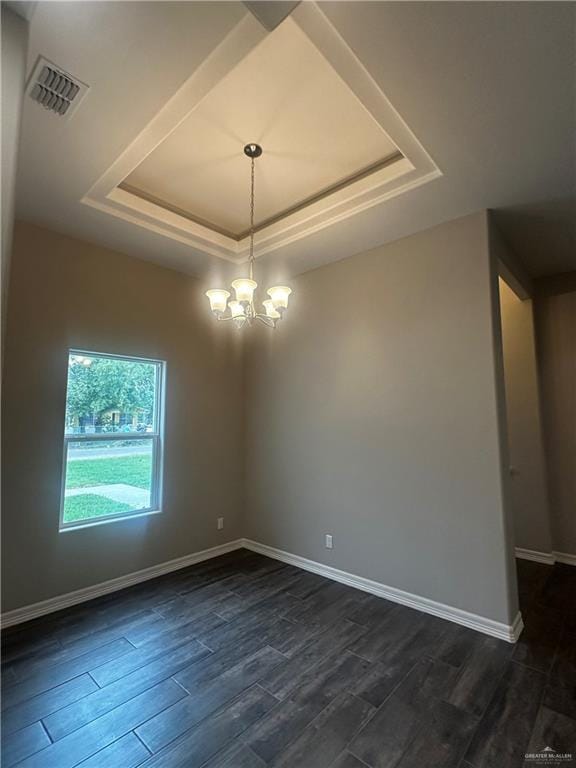 spare room with a tray ceiling, a chandelier, dark wood-type flooring, and baseboards