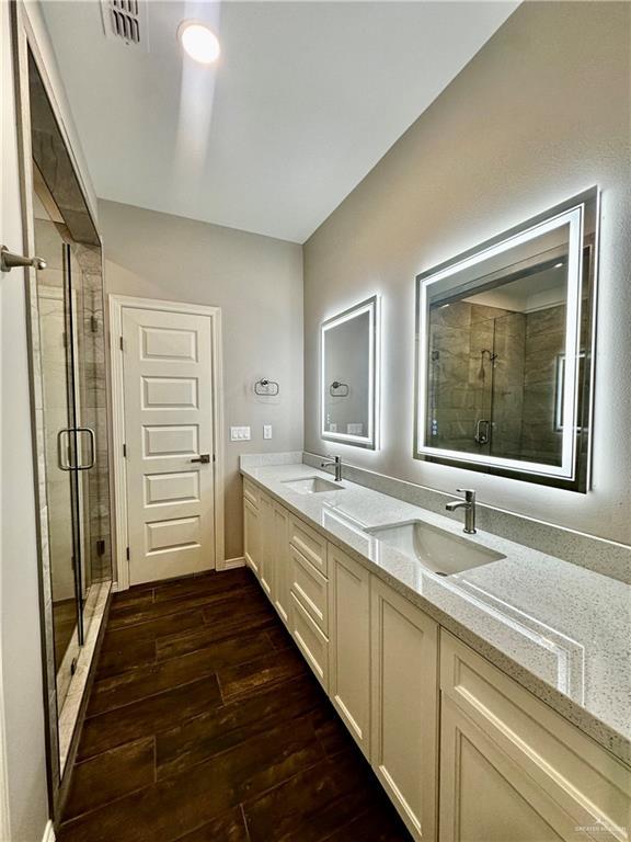 full bathroom with hardwood / wood-style floors, a stall shower, and double vanity