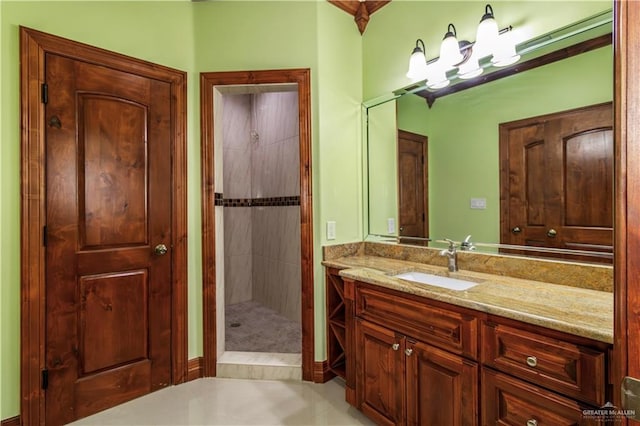 bathroom with vanity, a tile shower, and ornamental molding