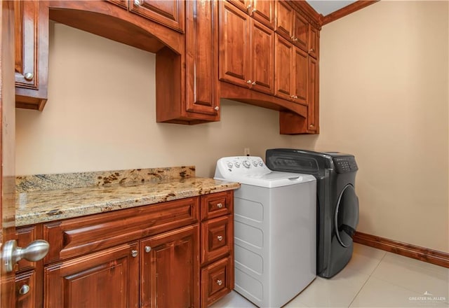 clothes washing area with separate washer and dryer, light tile patterned floors, and cabinets