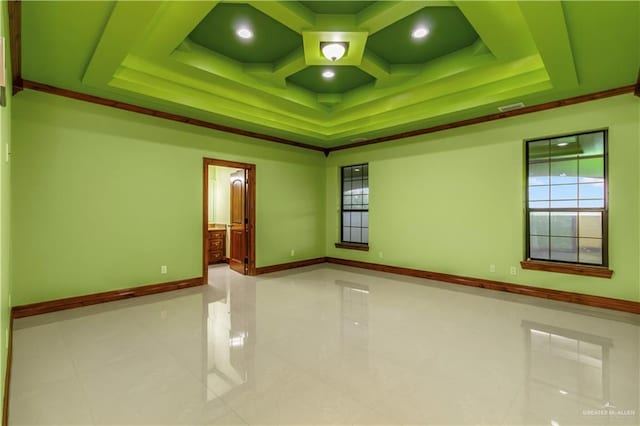 tiled spare room featuring a tray ceiling and ornamental molding