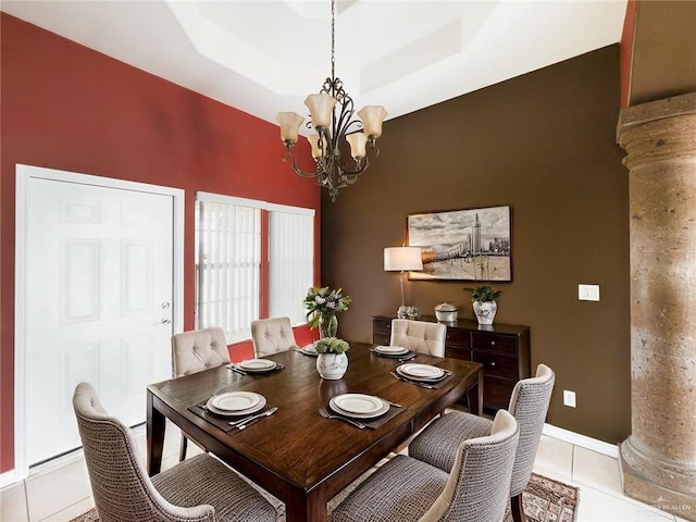 dining area featuring decorative columns, a raised ceiling, baseboards, an inviting chandelier, and light tile patterned flooring