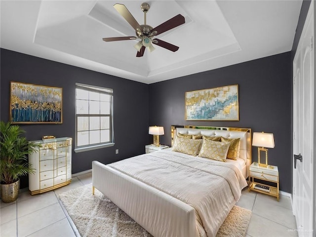 bedroom featuring a ceiling fan, baseboards, light tile patterned floors, and a raised ceiling