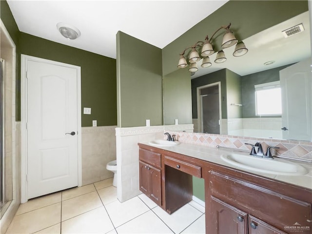 bathroom featuring tile patterned flooring, tile walls, a sink, and visible vents