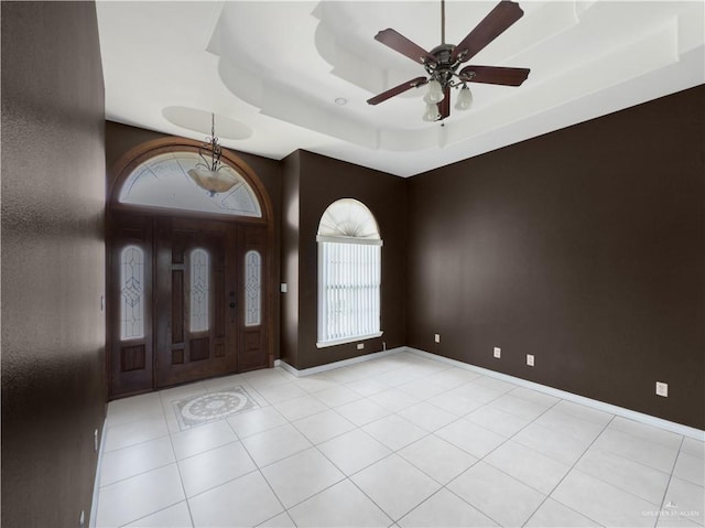 entryway featuring light tile patterned floors, a raised ceiling, baseboards, and a ceiling fan