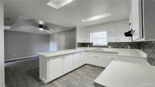 kitchen featuring white cabinetry, sink, backsplash, and kitchen peninsula