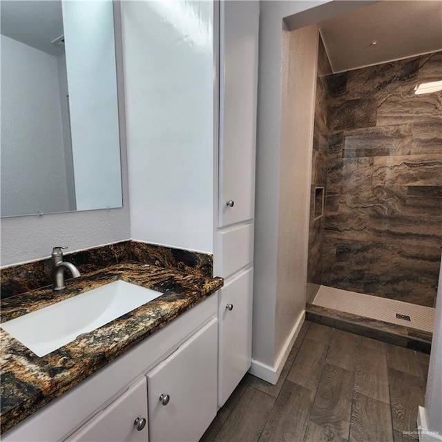 bathroom featuring vanity, hardwood / wood-style floors, and a tile shower