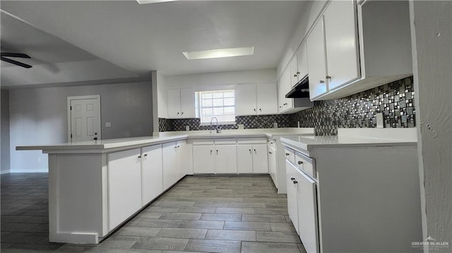 kitchen with kitchen peninsula, decorative backsplash, and white cabinets