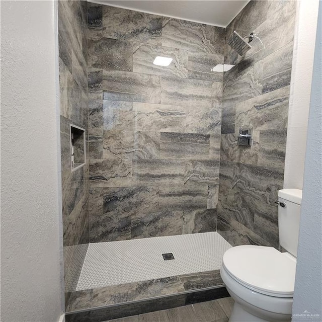 bathroom with tiled shower and toilet