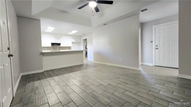 unfurnished living room featuring a tray ceiling, light hardwood / wood-style floors, and ceiling fan