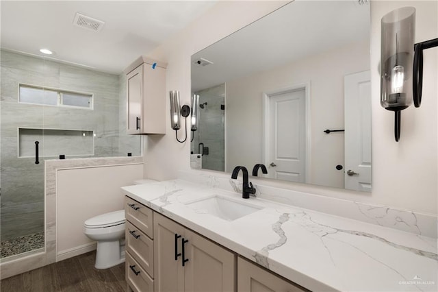 bathroom featuring a shower with door, vanity, wood-type flooring, and toilet