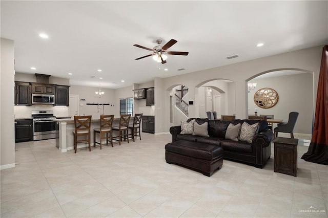 living room featuring recessed lighting, light tile patterned floors, arched walkways, and ceiling fan with notable chandelier